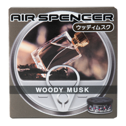 Air Spencer car air freshener packaging for 'Woody Musk' scent, featuring an image of a clear perfume bottle over dark wood, with a corresponding black and grey canister visible.